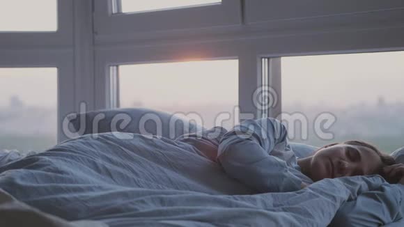 美丽浪漫的黑发女人睡在窗边的床上视频的预览图