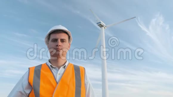 肖像男工程师投射风力机附近的工作晴天和云彩那人穿着一身红色的衣服视频的预览图