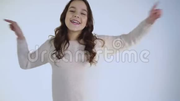 微笑欢快的女孩在白色背景镜头下跳舞的肖像视频的预览图