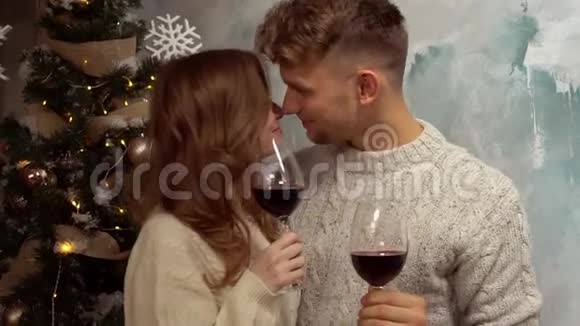 年轻夫妇在家一起过圣诞节在家概念举着酒杯接吻视频的预览图