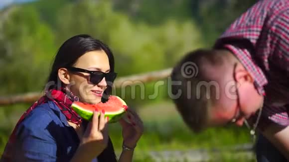 年轻人和女人在河边的森林里野餐吃西瓜4千克视频的预览图