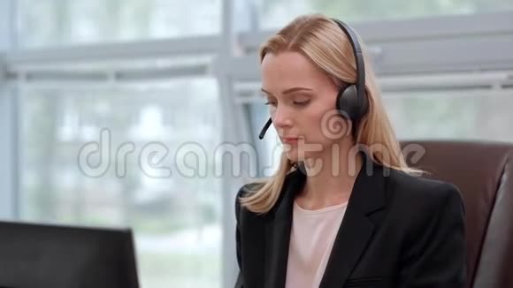 一个穿着黑色夹克的年轻漂亮的女人坐在办公桌前的行政椅上等等视频的预览图