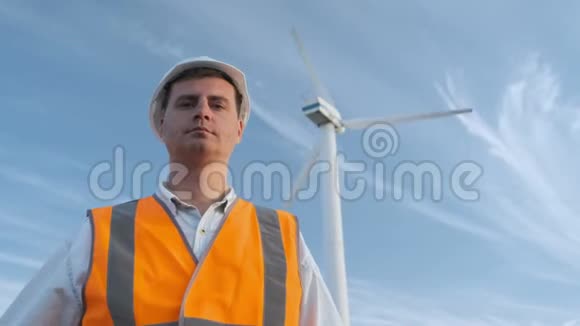 肖像男工程师投射风力机附近的工作晴天和云彩那人穿着一身红色的衣服视频的预览图