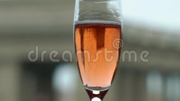 将粉红色香槟或起泡葡萄酒从瓶子中倒入玻璃杯中欧洲城市背景视频的预览图