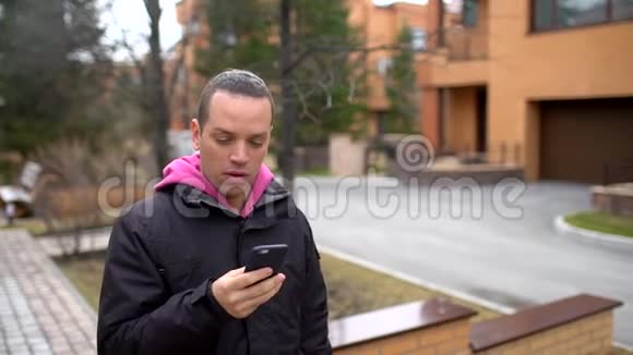 迷人的年轻人在公园里散步时用手机说话一个英俊的年轻人在打电话视频的预览图