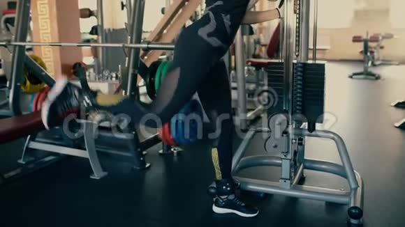 运动美丽的黑发中年妇女训练她的腿在电缆和滑轮机4千克视频的预览图