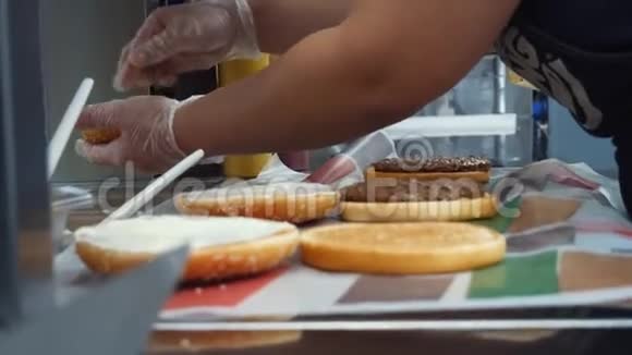 特写麦克唐纳工人烹饪经典汉堡与炸切片奶酪和蔬菜选择性关注框架视频的预览图