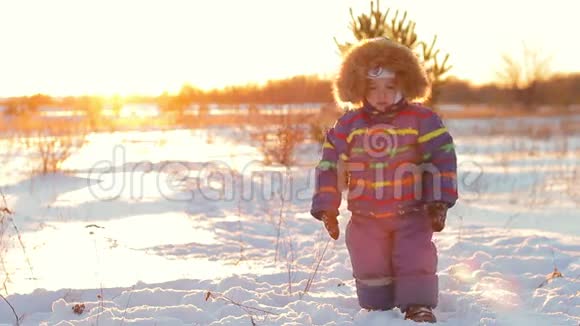 那个男孩正在日落时在雪地里散步视频的预览图