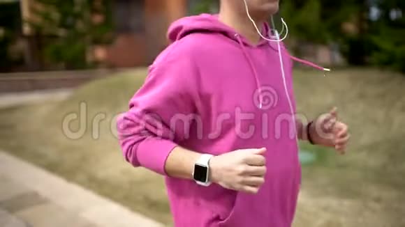 年轻的帅哥在公园晨跑时使用智能手表视频的预览图