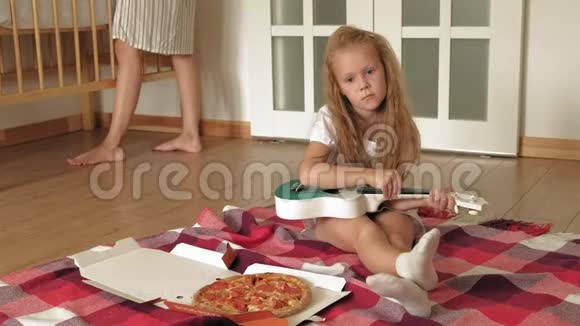 学龄前女孩在房间里坐在地板上吃披萨视频的预览图