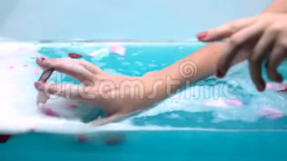女人用玫瑰花瓣和温和的泡沫泡浴放松视频的预览图