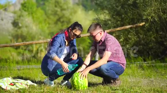 年轻人和女人在河边的森林里野餐吃西瓜合上洗西瓜4千克视频的预览图