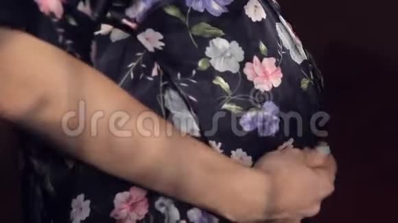 一个穿着丝绸长袍的怀孕少女小心翼翼地抚摸着肚子视频的预览图