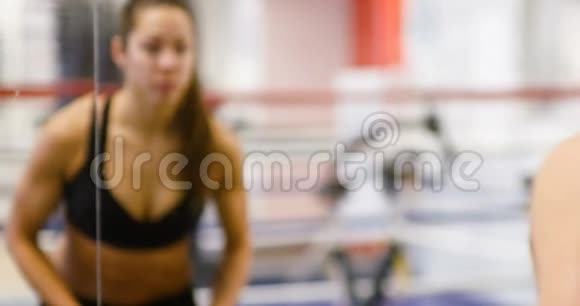 健康和训练有素的女性在健身健身房的镜子中举重视频的预览图