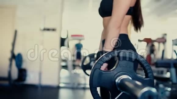 年轻漂亮的女孩长发在健身房做运动用杠铃在蹲4千克视频的预览图