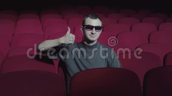 单身男子坐在黑色电影院舒适的红色椅子上竖起大拇指视频的预览图