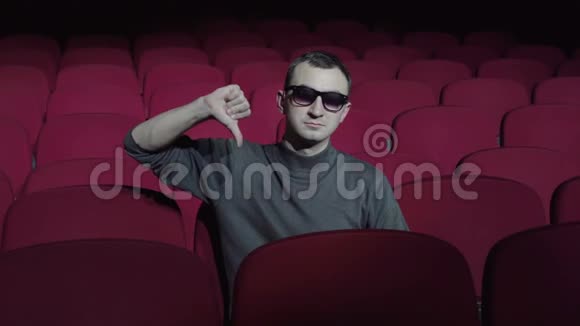 一个男人坐在黑暗电影院里舒适的红椅子上竖起大拇指视频的预览图