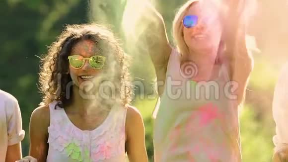 金发女人把五颜六色的粉末抛在快乐朋友的头上霍利节视频的预览图
