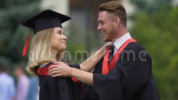 男毕业生温柔地拥抱他的女朋友微笑着人们享受生活视频的预览图
