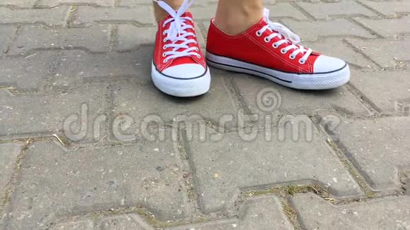 女人穿着红色运动鞋在城市的道路上视频的预览图
