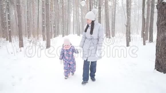母亲和女儿在雪地森林或公园散步视频的预览图