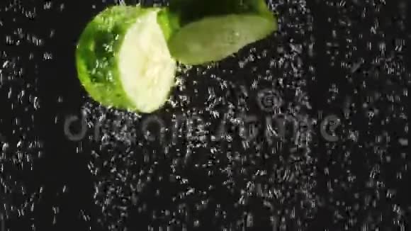 黄瓜和番茄片落入水中的黑色背景新鲜蔬菜在水中有气泡有机有机视频的预览图