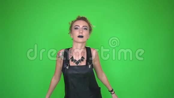 穿着黑色工作服的女人涂着黑色口红在绿色的彩色屏幕上跳舞视频的预览图