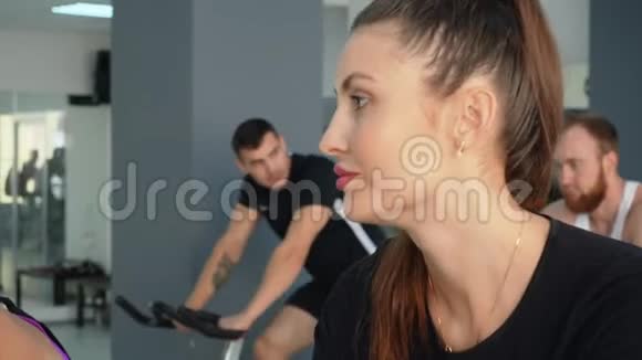 微笑的女人骑着运动自行车去健身房视频的预览图