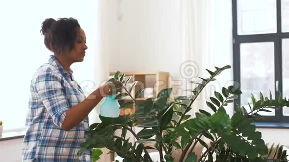 快乐的女人在家里喷洒植物视频的预览图