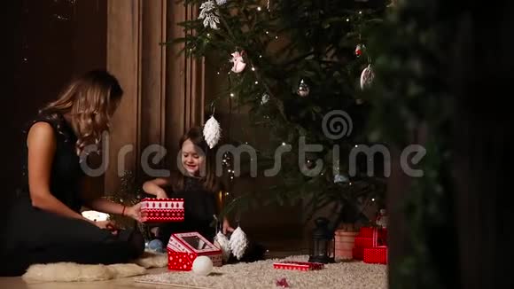 一个女孩和她妈妈正在圣诞树下收集新年礼物视频的预览图