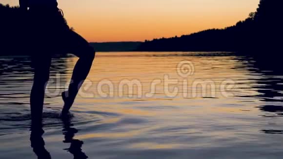 女人的腿优雅优雅地走在红霞夕阳下的湖中视频的预览图