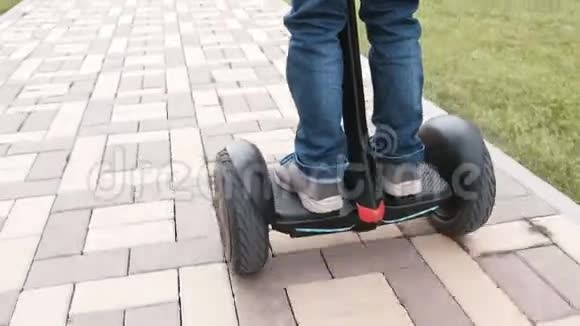 无法辨认的男孩正在家附近骑着陀螺滑板车后景腿部特写视频的预览图
