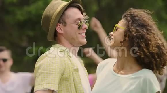 戴帽子的酷男和在露天派对上笑跳舞的混血女孩视频的预览图