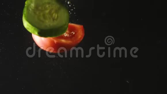 黄瓜和番茄片落入水中的黑色背景新鲜蔬菜在水中有气泡有机有机视频的预览图