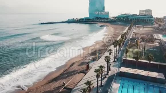 鸟瞰美丽的海岸线现代建筑游泳池和人们在蓝天的海滩上散步视频的预览图