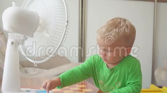 童年家的概念可爱的小男孩与大冷却风扇视频的预览图