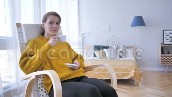 放松的女人坐在休闲椅上喝咖啡视频的预览图