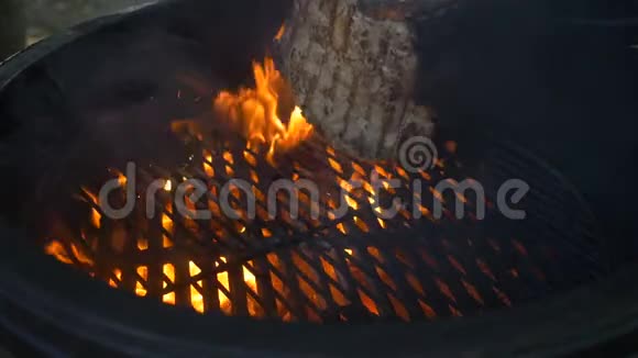烧烤厨师用铁钳把一块多汁的牛肉或羊肉翻过来火在燃烧冒烟视频的预览图