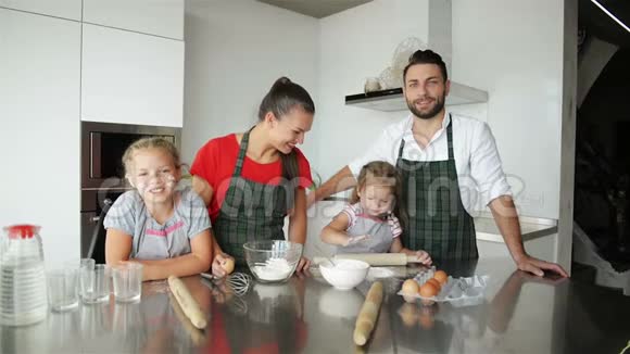 一起做饭他们在厨房里玩得很开心可爱的女儿和他们英俊的父母玩视频的预览图
