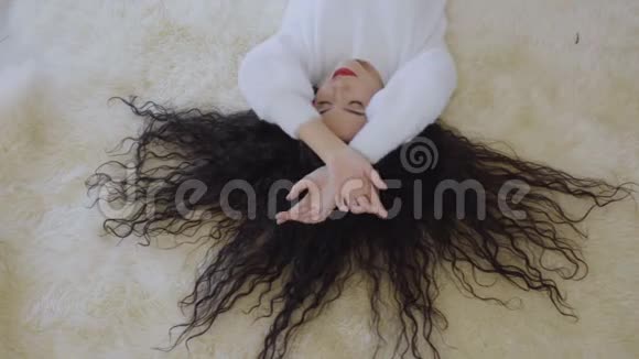美丽的女孩躺在地毯上用耳机听音乐视频的预览图