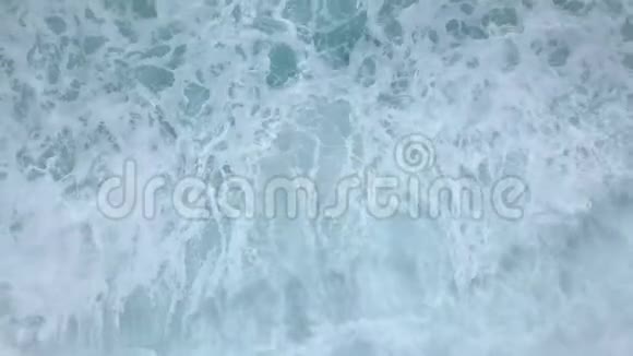 空中俯视图海浪在空荡荡的海滩上翻滚破碎溅起泡沫视频的预览图