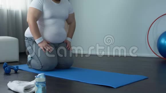 在家中锻炼时胖子在垫子上练习木板锻炼意志力量目标视频的预览图