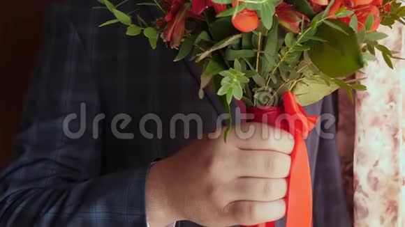 有美丽花朵的商人穿着红领带和白色夹克的男人手中捧着一束美丽的红玫瑰视频的预览图