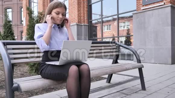 女子听音乐及在外办公大楼笔记本电脑视频的预览图