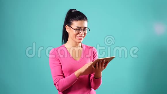 这位年轻女孩微笑着在平板电脑上与朋友广泛交流这个女孩看起来很可爱很开心视频的预览图