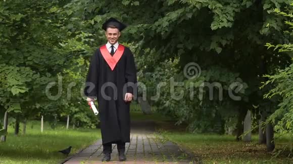 笑容满面的年轻人穿着学院服手里拿着毕业证书高兴得跳了起来视频的预览图