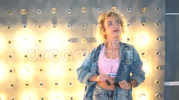 性感卷曲的金发女孩在明亮的背景下跳舞视频的预览图