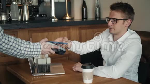 使用手机支付咖啡费用的人使用NFC咖啡厅服务员手持的阅读器视频的预览图