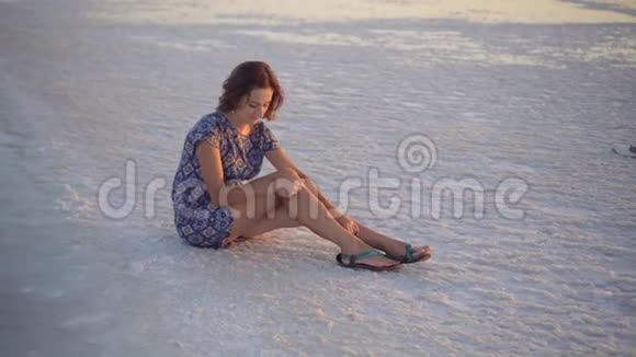 风平浪静的女孩享受阳光坐在靠近湖边的满是盐的地上视频的预览图