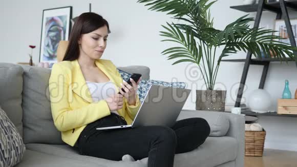 女人用智能手机坐在沙发上上网视频的预览图